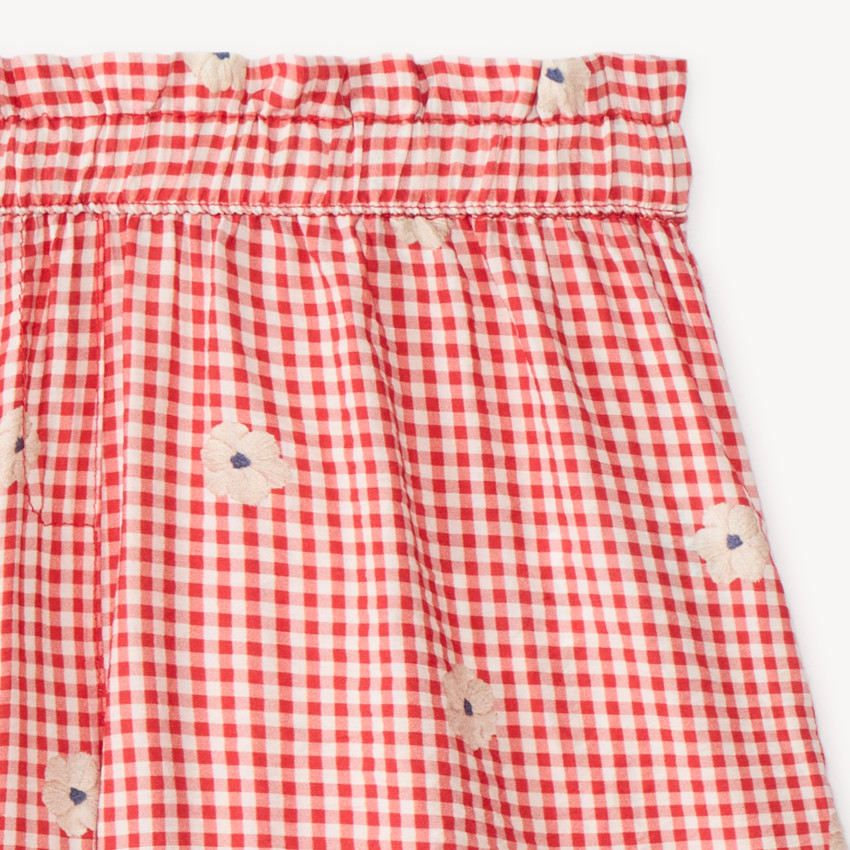 Kort meisje met vichy-stijl en geborduurde bloemen 