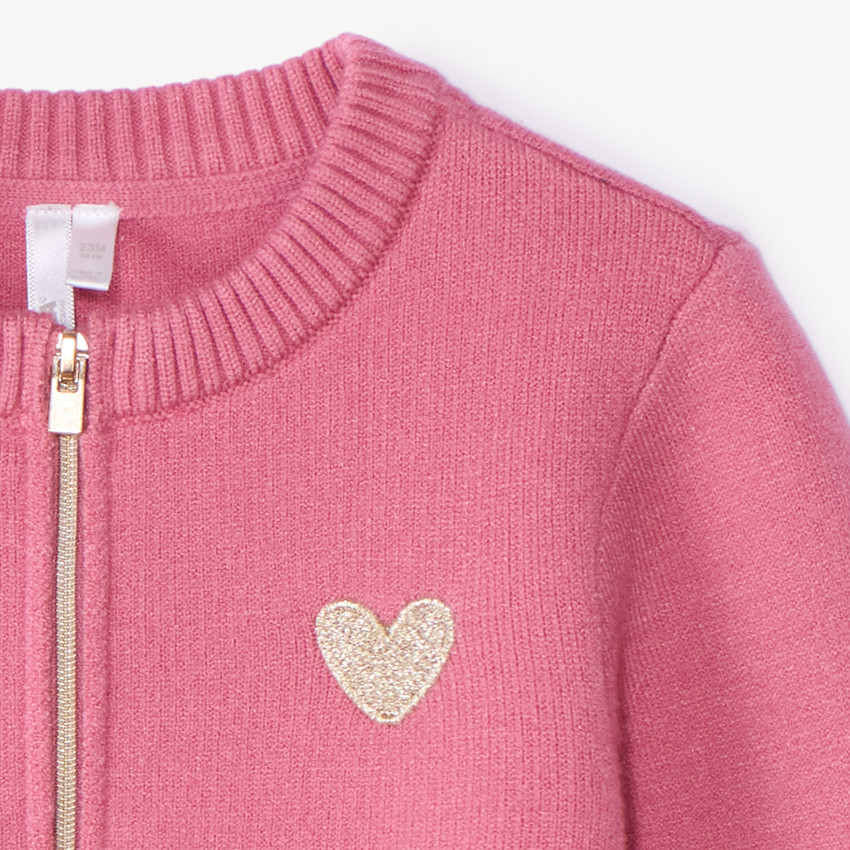 Gemaakt van gebreid materiaal, deze meisjes gilet met rits heeft een stijlvolle pasvorm. 